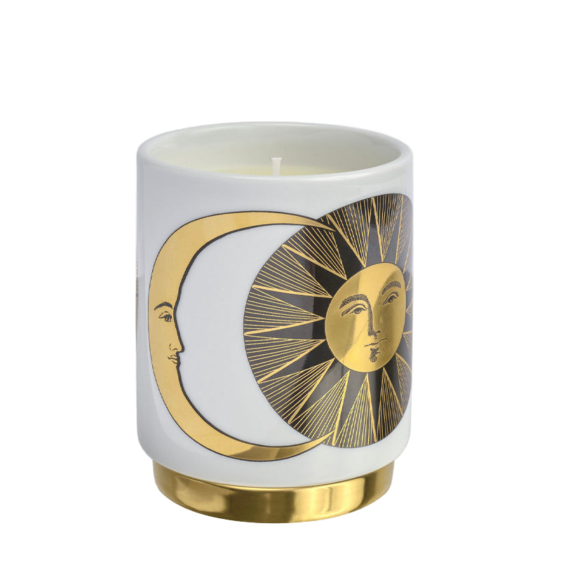 Candle in a white container with gold sun and moon design on a white background