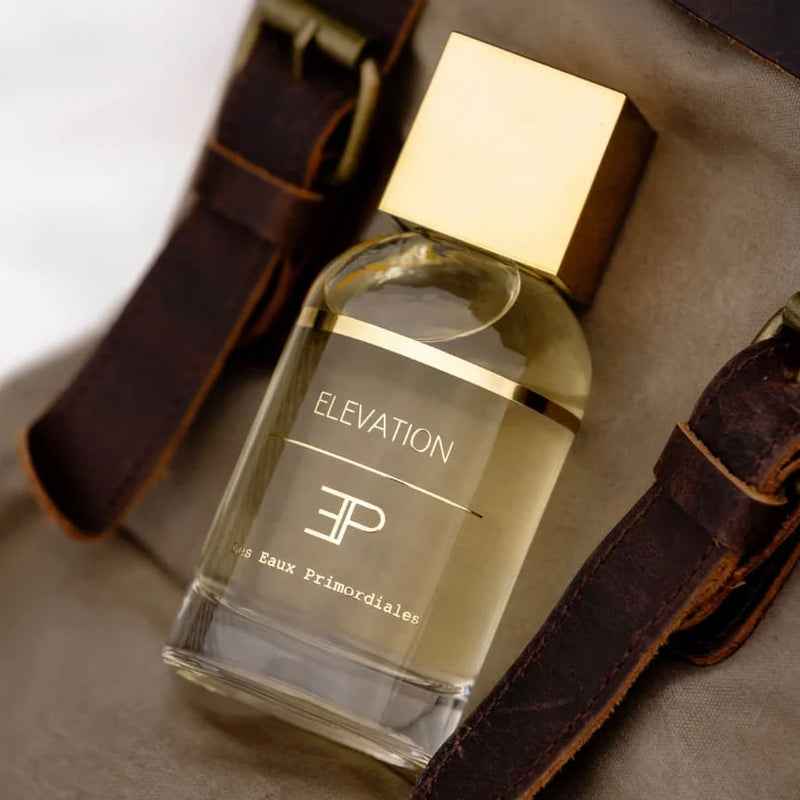 Perfume bottle labeled 'Elevation' with gold cap on a textured surface.