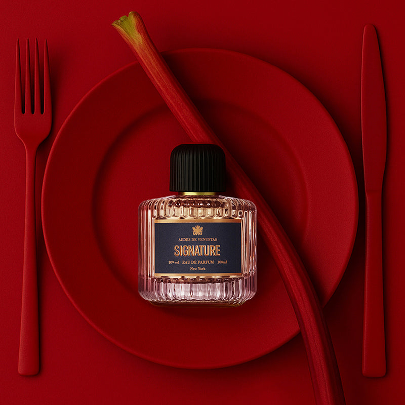 Perfume bottle labeled 'Signature' on a red plate with cutlery