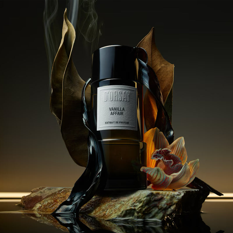 Black fragrance flacon by D'Orsay on a background with a smoky leaf and an orchid. Flacon is sitting on a marble rock surrounded by whater. White square label reads D'Orsay Vanilla Affair Extrait de Parfum. Size is 3oz