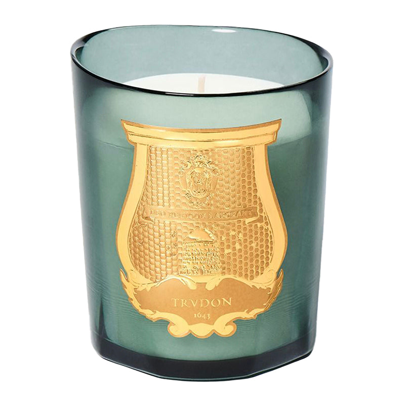 Candle in a green glass container with gold decorative emblem and 'Trudon' branding. Figuerie - Candle | Trudon 