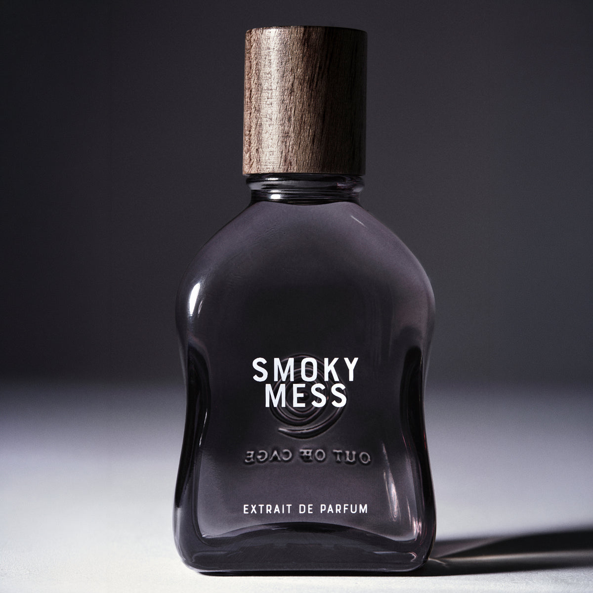 Smoky Mess - Extrait de Parfum | Out Off Cage | Gray Flacon with Wooden cap on gray backdrop reading SMOKY MESS Extrait de Parfum