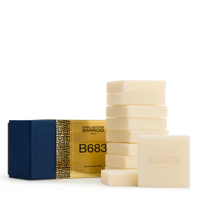 A set of ten Marc-Antoine Barois B683 guest soap bars in a cream color, shown alongside their packaging: a gold and navy blue box with a geometric pattern.