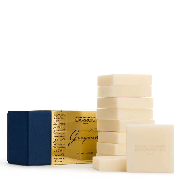 A set of Marc-Antoine Barrois guest soap bars and packaging on a clean white background. The set includes a stack of cream-colored soap bars, a single bar in front embossed with 'MARC-Antoine BARROIS PARIS', and a blue box next to a gold foil envelope with 'Ganymede' written on it.