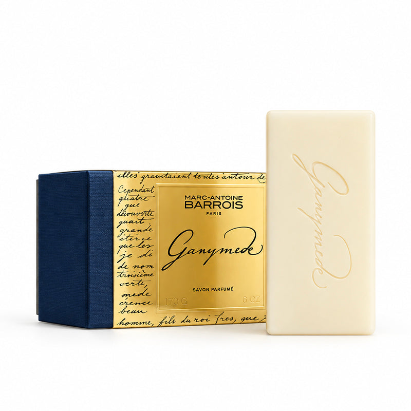 Marc Antoine Barrois Ganymede natural soap bar next to its gold and navy blue packaging box, on a clean white background.