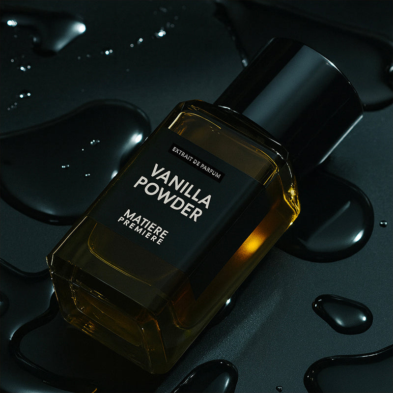 Perfume bottle labeled 'Vanilla Powder' on a dark background with water droplets.